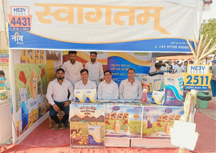 Early Neev Seeds trade-show stall with a plain welcome banner and a table